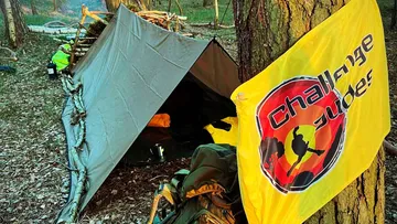 Camping tarp and gear in forest setting.