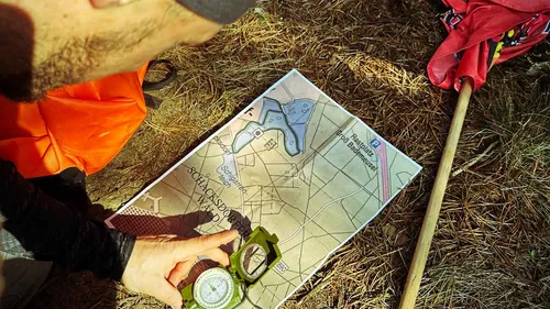 Person using compass on map outdoors.
