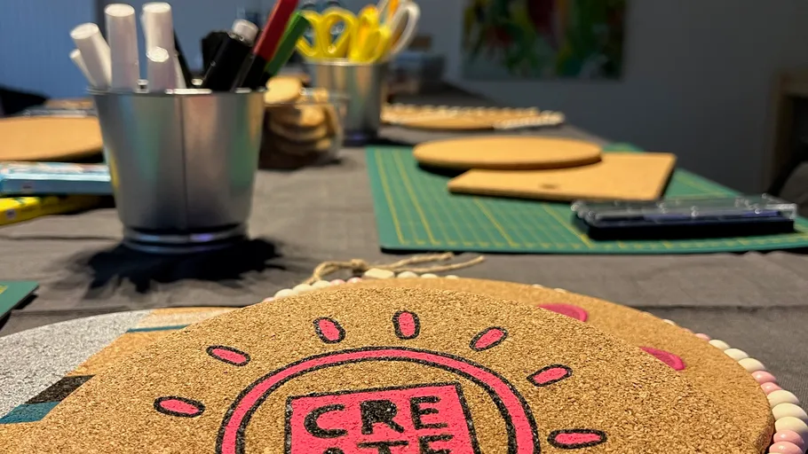 Basteltisch mit Materialien und runder Korkdekoration.