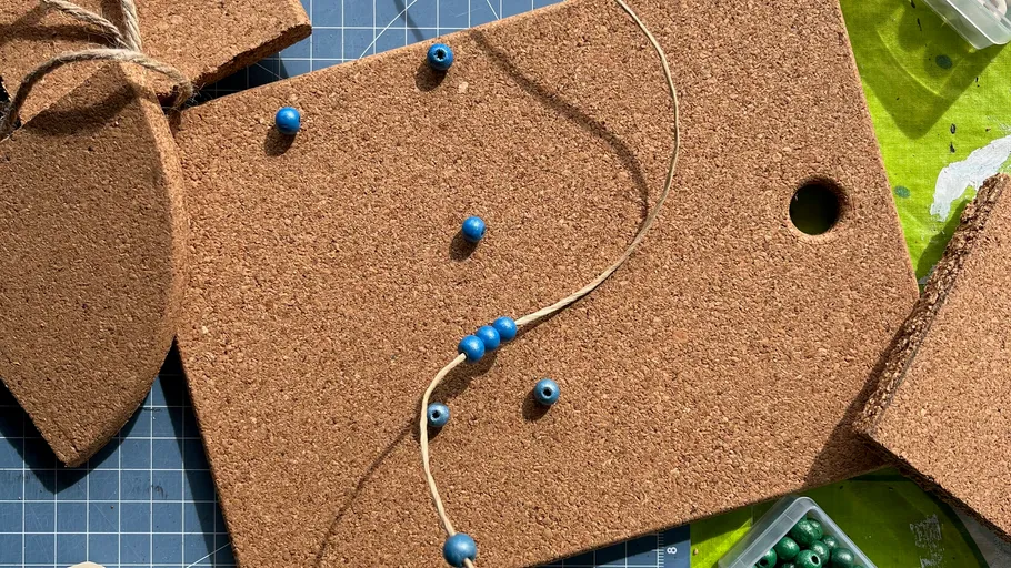 Cork board with string and blue beads.