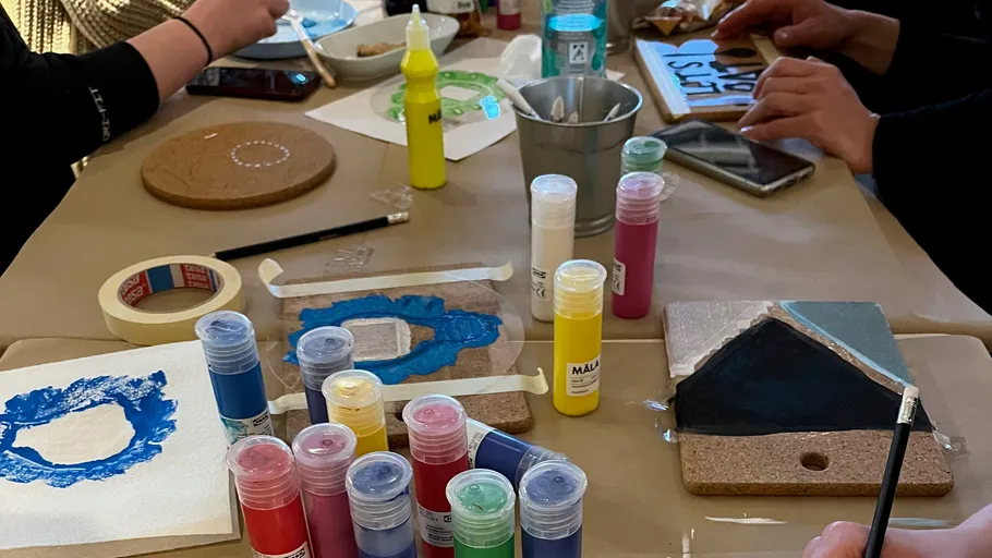 People painting on coasters at a table.