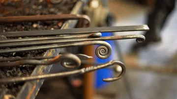 Metal rods with ornate spirals in workshop.
