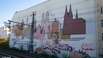 Colorful mural on building near train tracks.
