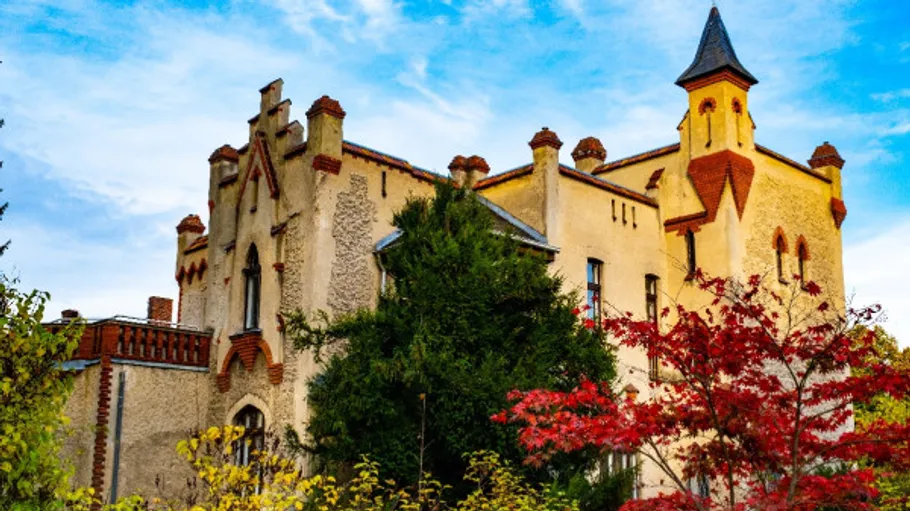 Historic castle with autumn foliage surrounding.