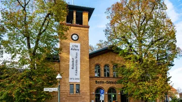 Historic railway station building surrounded by trees.
