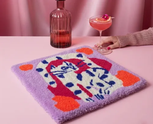 Decorative rug on pink table with drink.