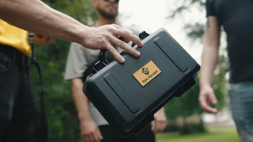 Hand holding a black case outdoors.