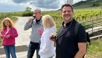 Vier Personen trinken im Weinberg.