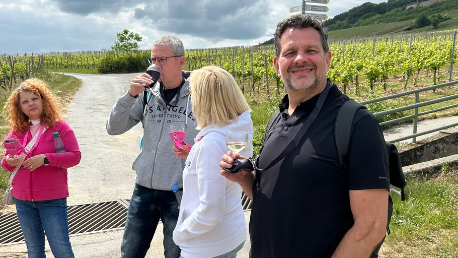 Four people enjoying drinks in vineyard.