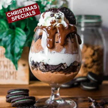 Layered dessert in glass with chocolate and cookies.