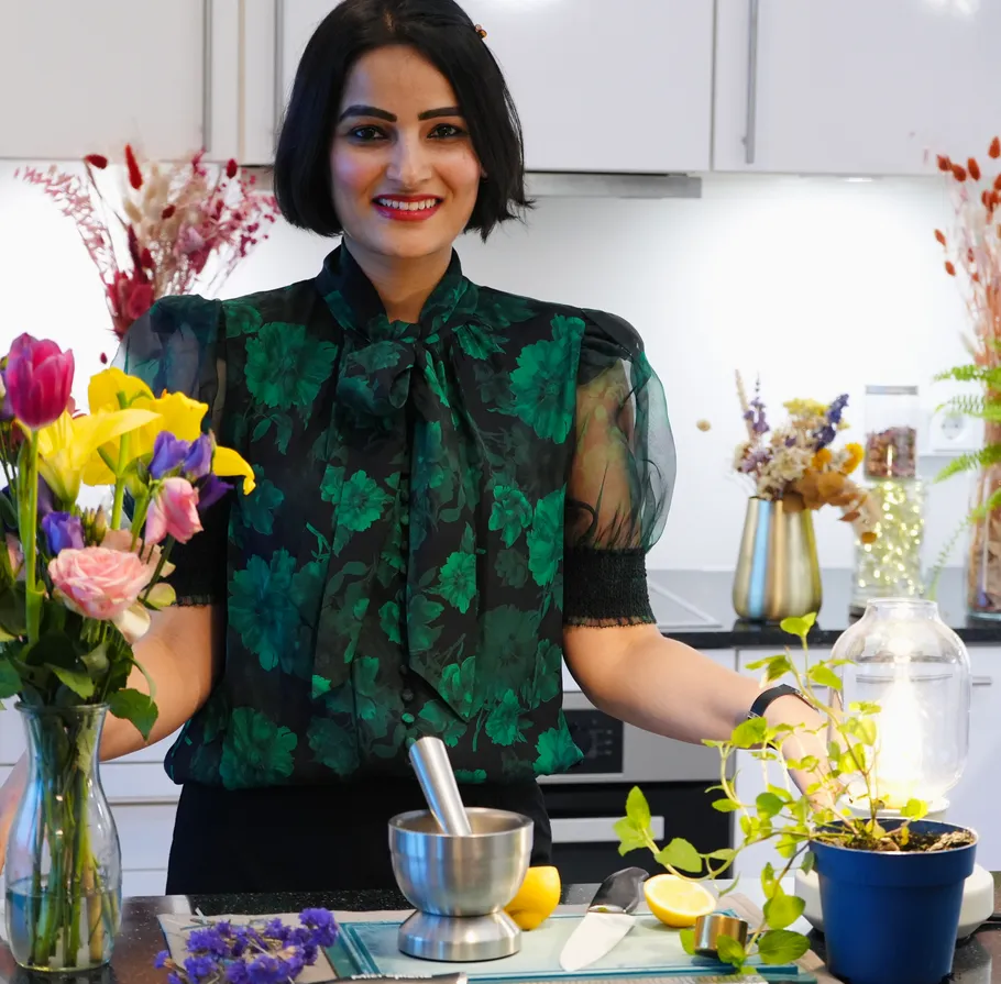 Person smiling in kitchen with flowers.