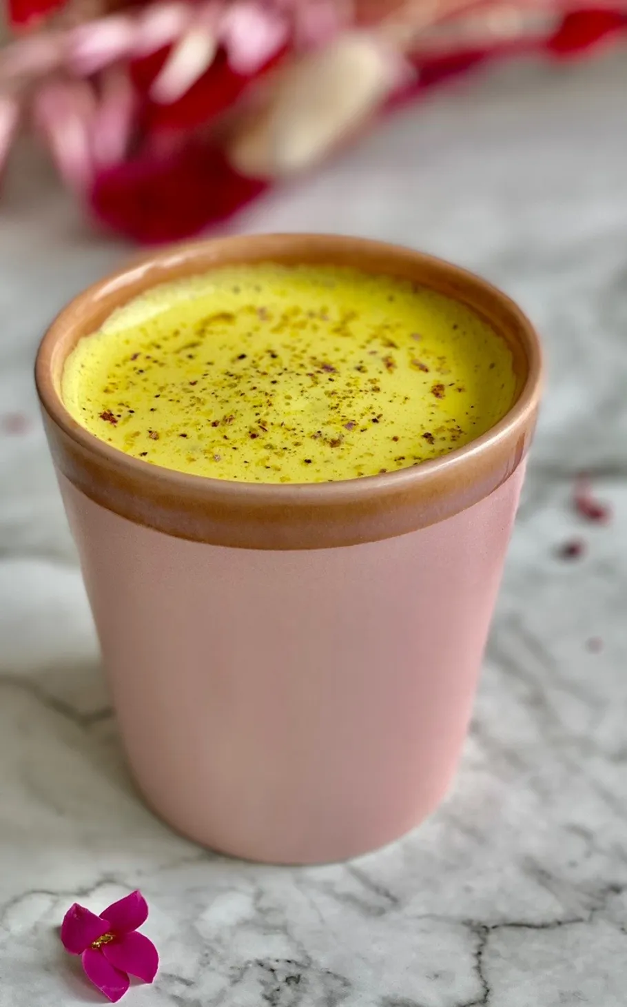 Cup of turmeric latte on marble table.