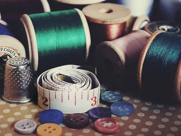 Spools, tape measure and buttons on a patterned fabric.