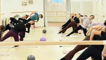 People stretching in a ballet studio.