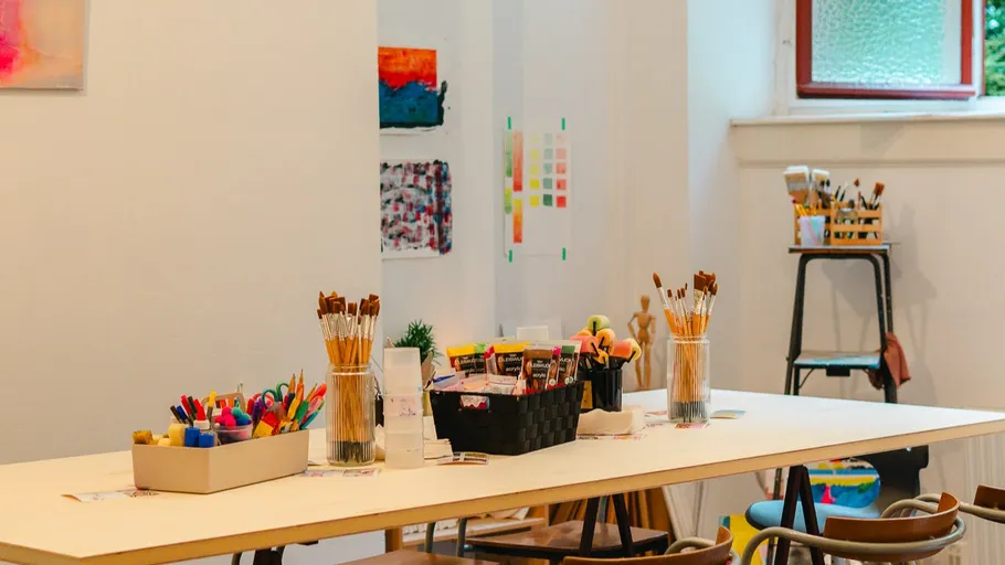 Art studio table with supplies and paintings.