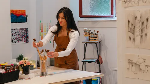Woman organizing paintbrushes in art studio.