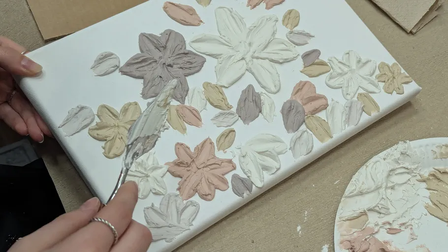 Hand painting flowers on canvas with spatula.