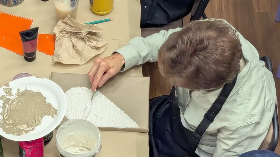 Person applying paint in an art class.