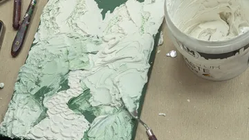 Strukturiertes Gemälde mit Werkzeugen und Paste.