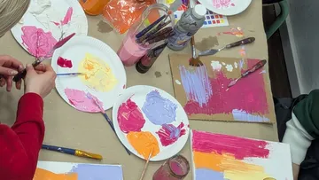 Menschen malen mit bunten Farben auf Papier.
