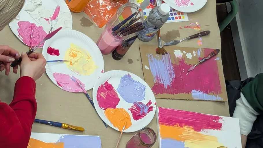 People painting with colorful paints on paper.