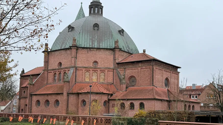 Brick church with large dome in autumn surroundings.
