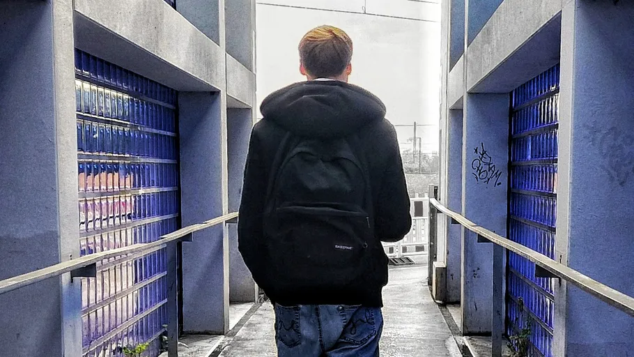 Person geht auf einem Weg zwischen Wänden.