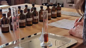 Person writing near various labeled bottles.