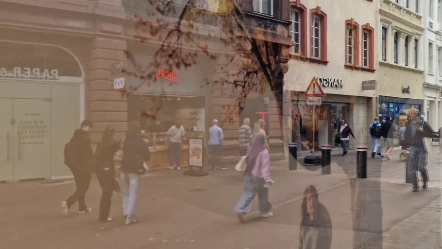 Pedestrians walking on urban street with reflections.