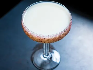 Ein Cocktailglas steht auf einer dunklen Oberfläche.