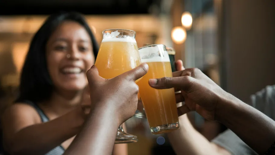 Smiling people toasting with beer glasses indoors.