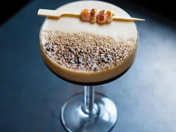 Ein Cocktail steht auf einem Tisch mit angebranntem Zucker.