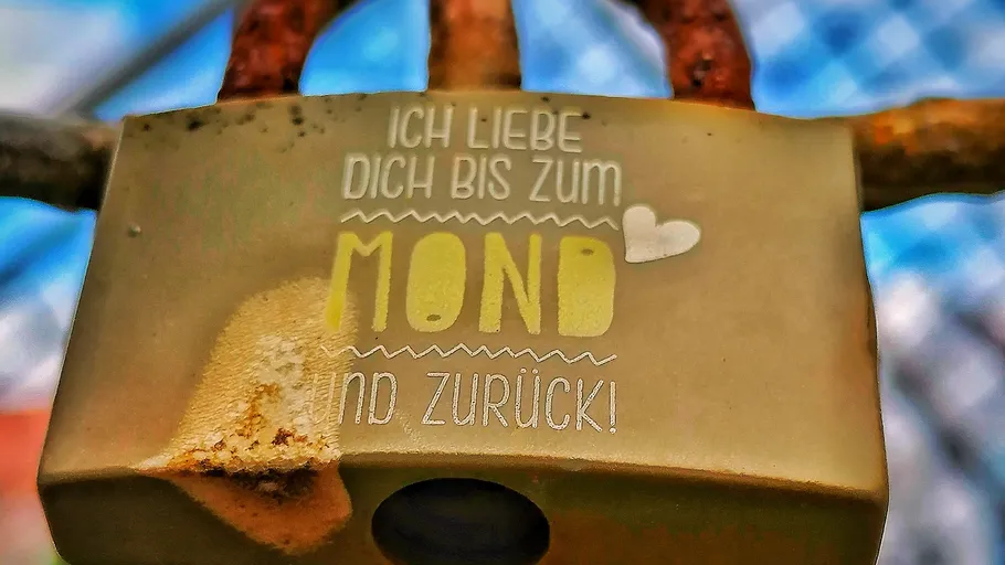 Vorhängeschloss mit Liebesbotschaft am Zaun befestigt.