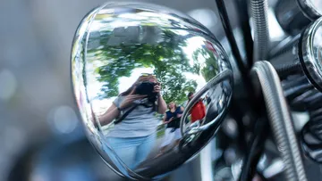 Reflection of photographer in motorcycle mirror.