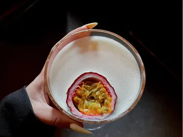 Cocktail mit Passionsfrucht, gehalten in einer Hand.
