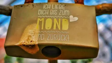 Rusty padlock on metal railing, love message.