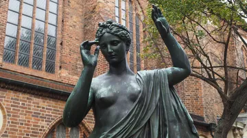 Bronzestatue einer Frau nahe Kirche.