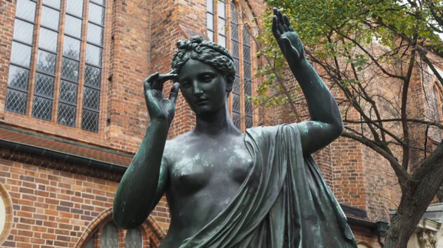 Bronze statue of a woman near church.