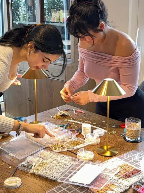 Two women making jewelry at a table.