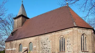 Historische Kirche mit Holzturm, blauer Himmel.