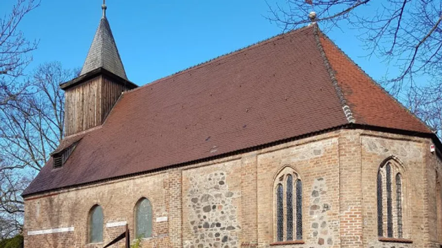Historische Kirche mit Holzturm, blauer Himmel.