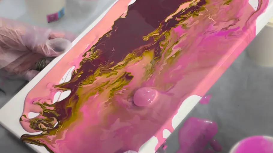 Pink and gold paint poured onto canvas.
