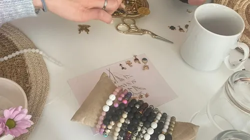 Hands arranging jewelry on a table.