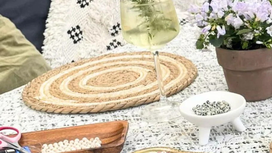 Cocktail glass, craft supplies on lace-covered table.