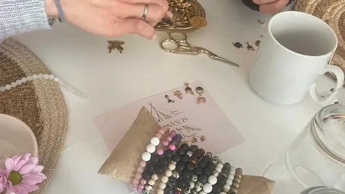 Hands crafting jewelry at a table.