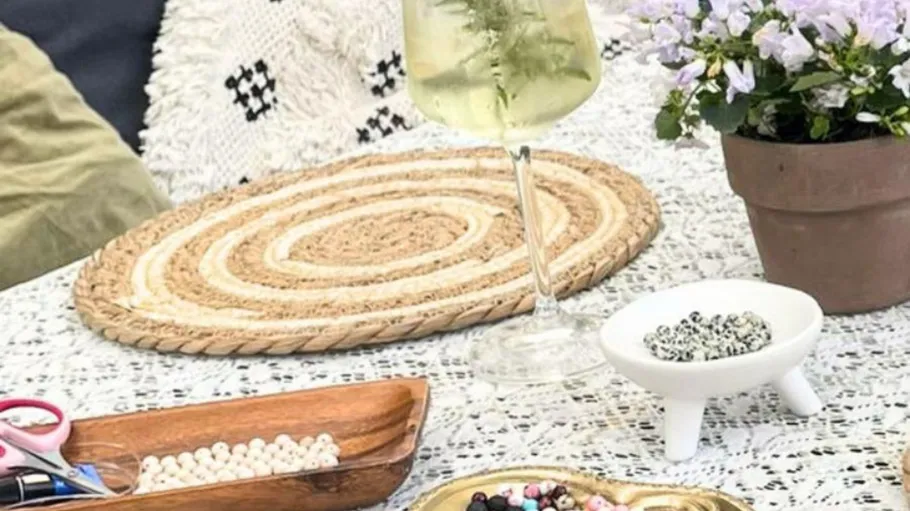 Bastelmaterialien und Getränk auf Spitzentischdecke.