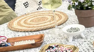 Beads, wine, and flowers on outdoor table.