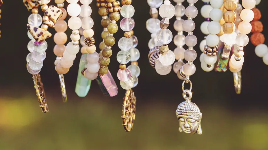 Colorful beaded necklaces with charms hanging outdoors.
