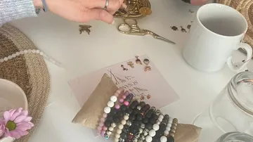 Hands arranging jewelry on a table.