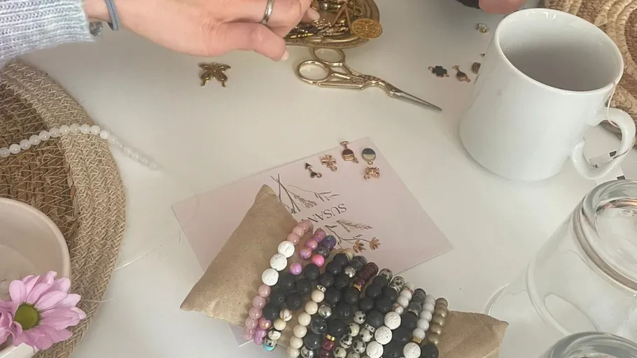 Hände arrangieren Schmuck auf einem Tisch.